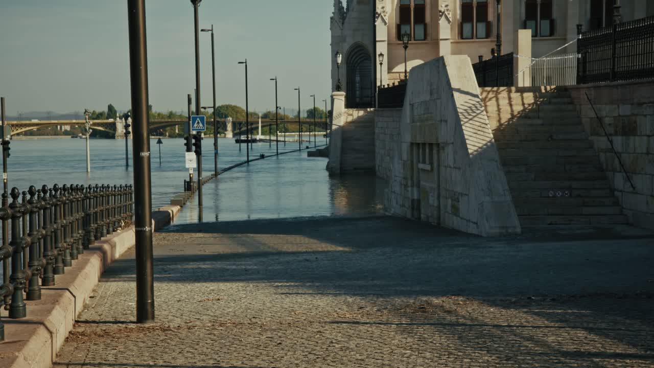 Flooded streets near the Parliament building in Budapest, with rising water surrounding trees and parking signs