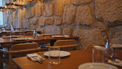 interior del restaurante con pared de piedra y mesas de madera