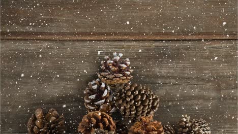 Animation-of-snow-falling-over-pine-cones-on-wood-boards