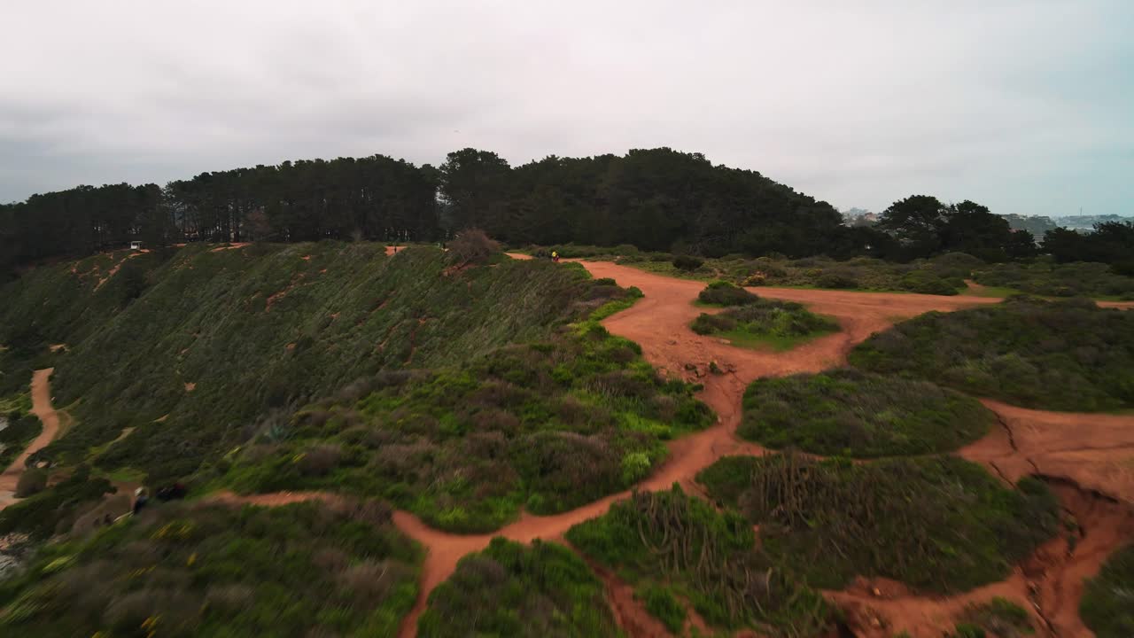 Forward drone aerial over the rocky Pacific coast and cliff trail, Valparaiso Region, Chile, on an overcast day