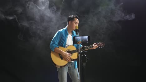 man singing and playing acoustic guitar