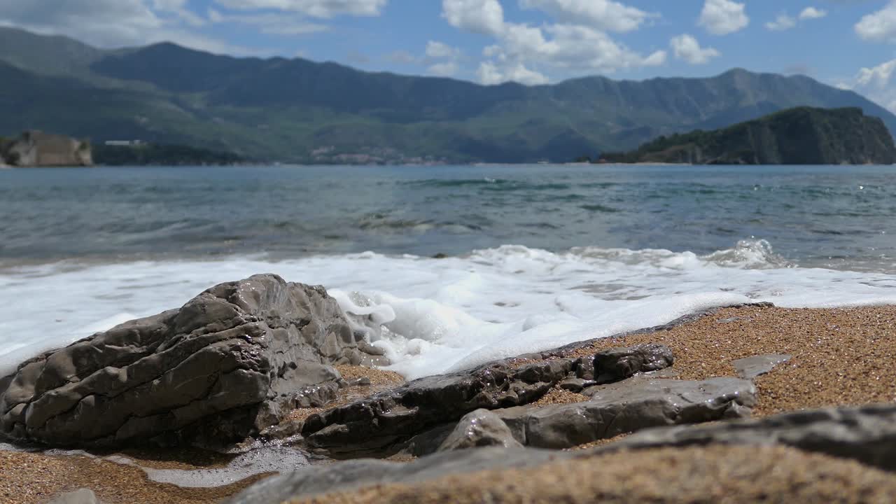 Onde che accarezzano dolcemente la sabbia su una spiaggia bella e naturale, primo piano.