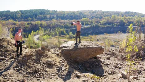 strong athletes exercises with sport equipment outdoors. two shirtless sportsmen lifting heavy weights on the nature background.