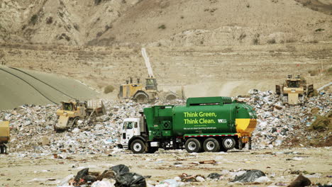 a green waste management garbage truck and heavy machinery at a large landfill