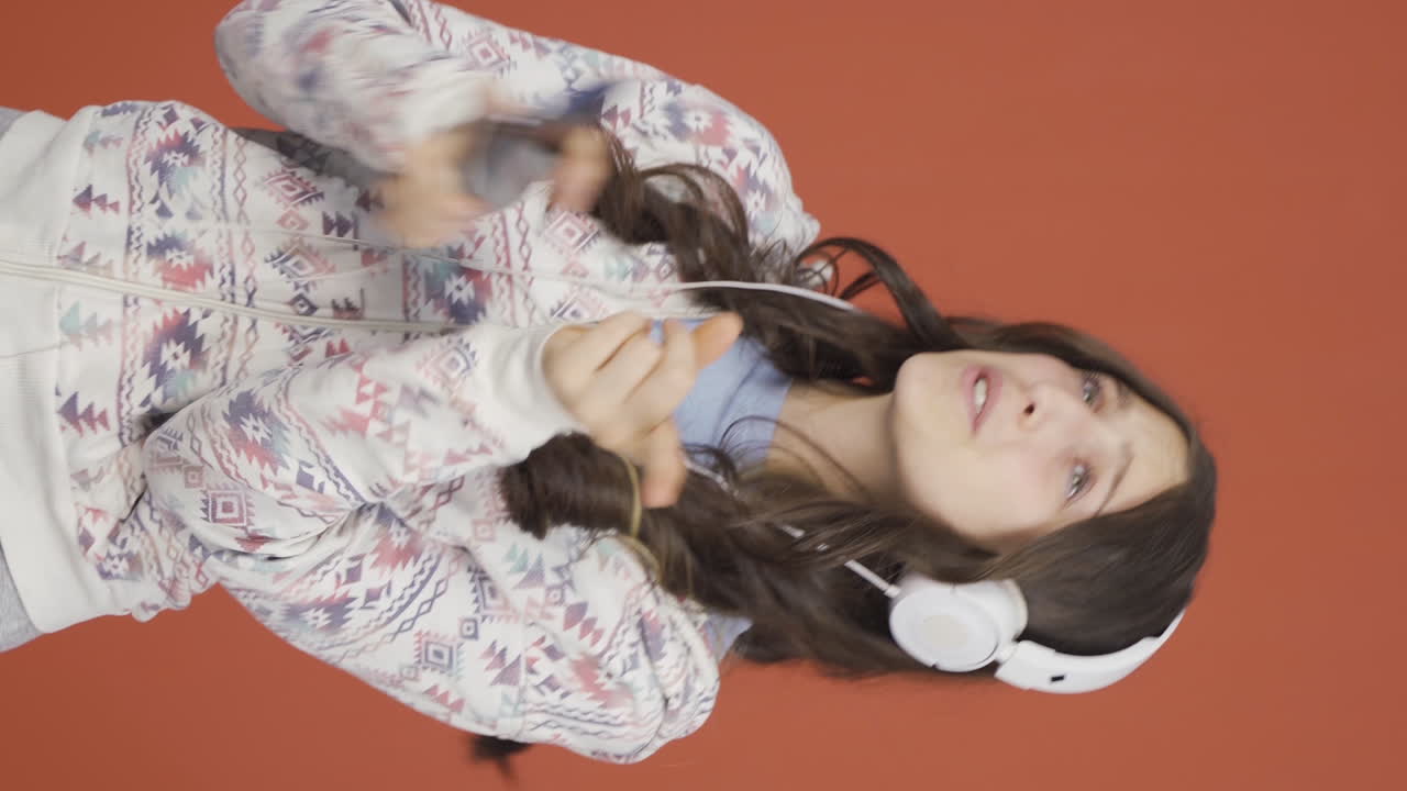 video vertical de una mujer joven bailando con el teléfono en la mano.