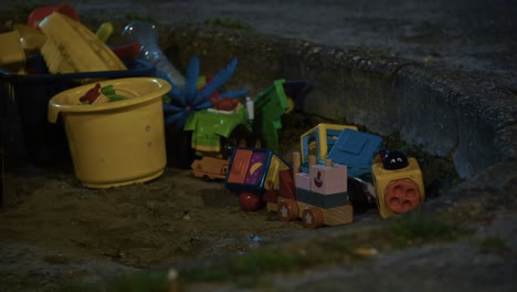colorful toys left in zagreb sandbox at night under soft artificial lighting