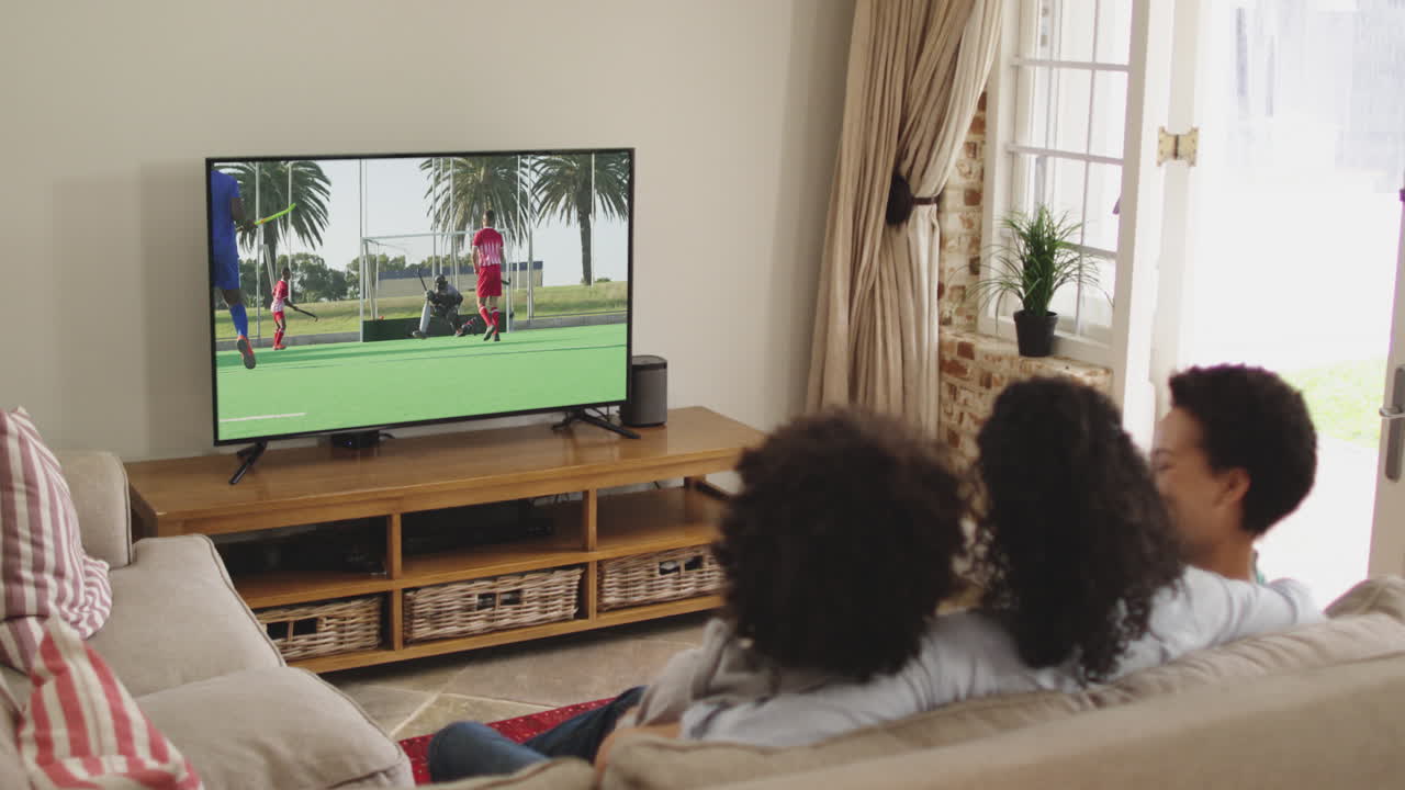 Famiglia felice seduta a casa insieme che guarda una partita di hockey in TV