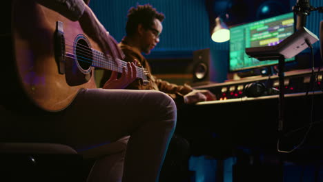 creative musician singing guitar in professional studio control room