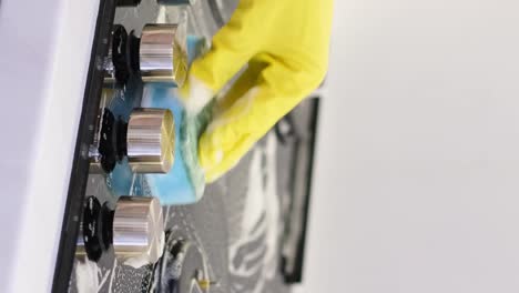 cleaning kitchen gas stove. womans hand cleaning gas stove with sponge