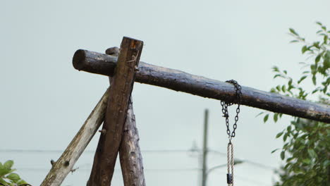 wooden handmade children's swing in a backyard on a rainy day