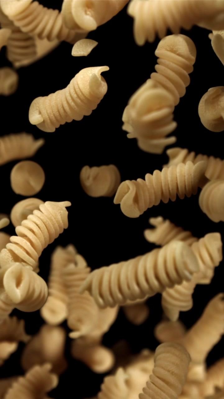 Uncooked Fusilli Pasta Falling in Slow Motion on Black Background