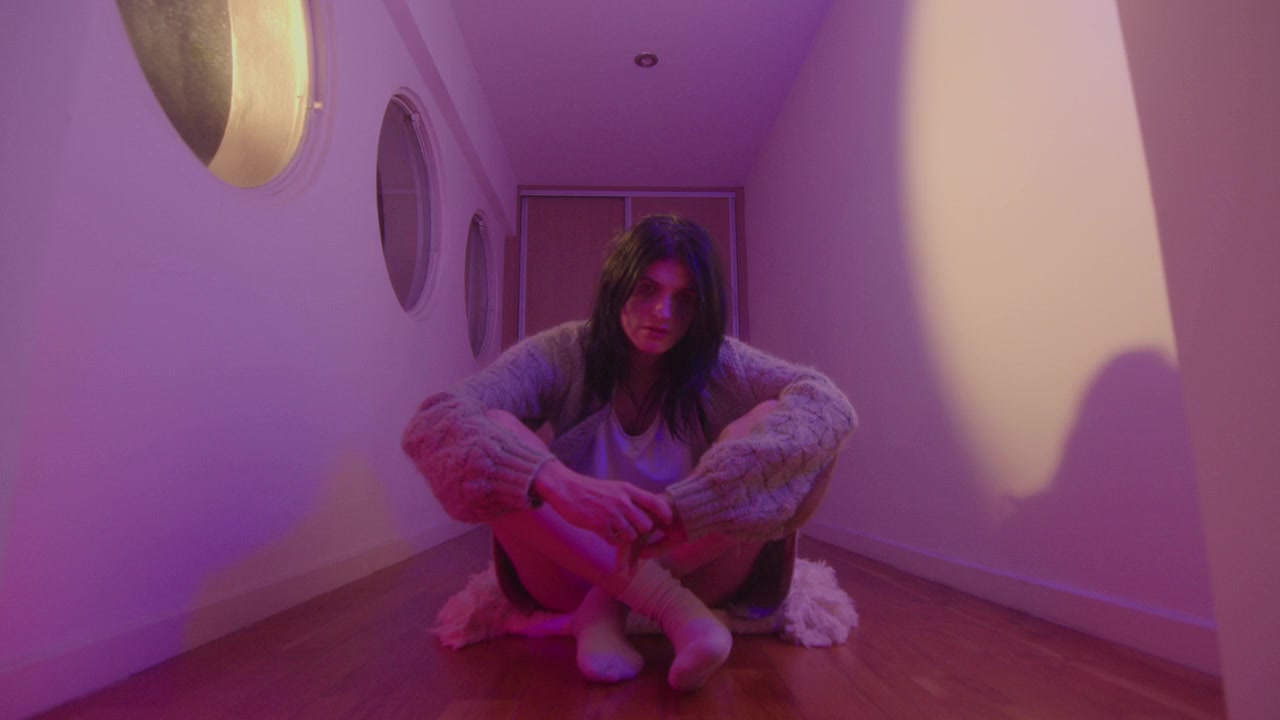 Niña llorando sentada en un pasillo con luz de neón