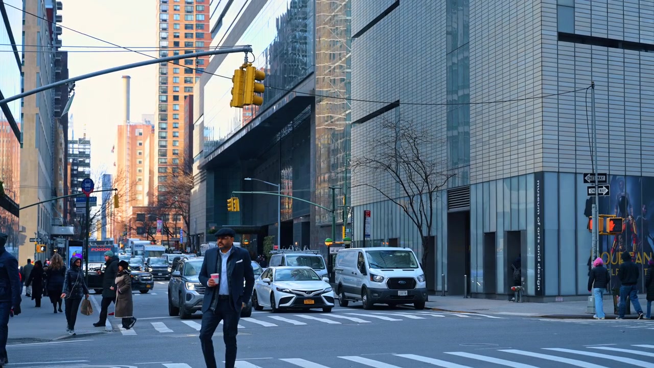 New York, USA, 15 April 2026: Street scene with pedestrians crossing near Museum of Arts and Design. People walking across a Manhattan street with modern architecture and traffic lights in New York
