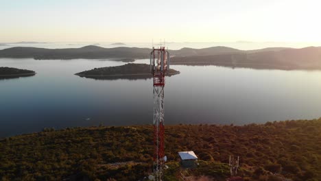 Close-Aerial-pull-past-a-Telecom-Tower-located-on-a-hillside-overlooking-sunset-islands-in-the-Adriatic-Sea