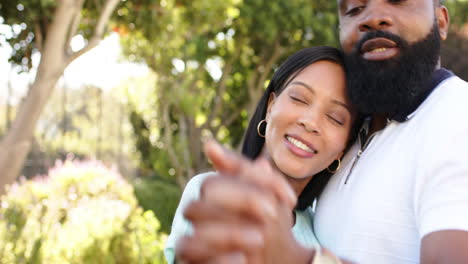 biracial woman and african american man smiling together outdoors in lush garden