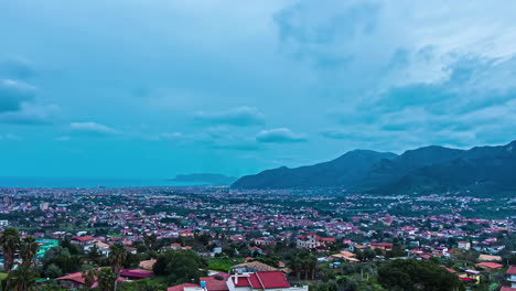 High-angle-shot-over-a-city-by-the-seaside-during-evening-time-with-the-view-of-mountain-range-in-the-background-in-Sicily-Italy