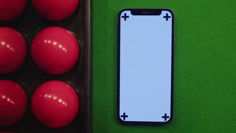 smartphone on snooker table with red balls