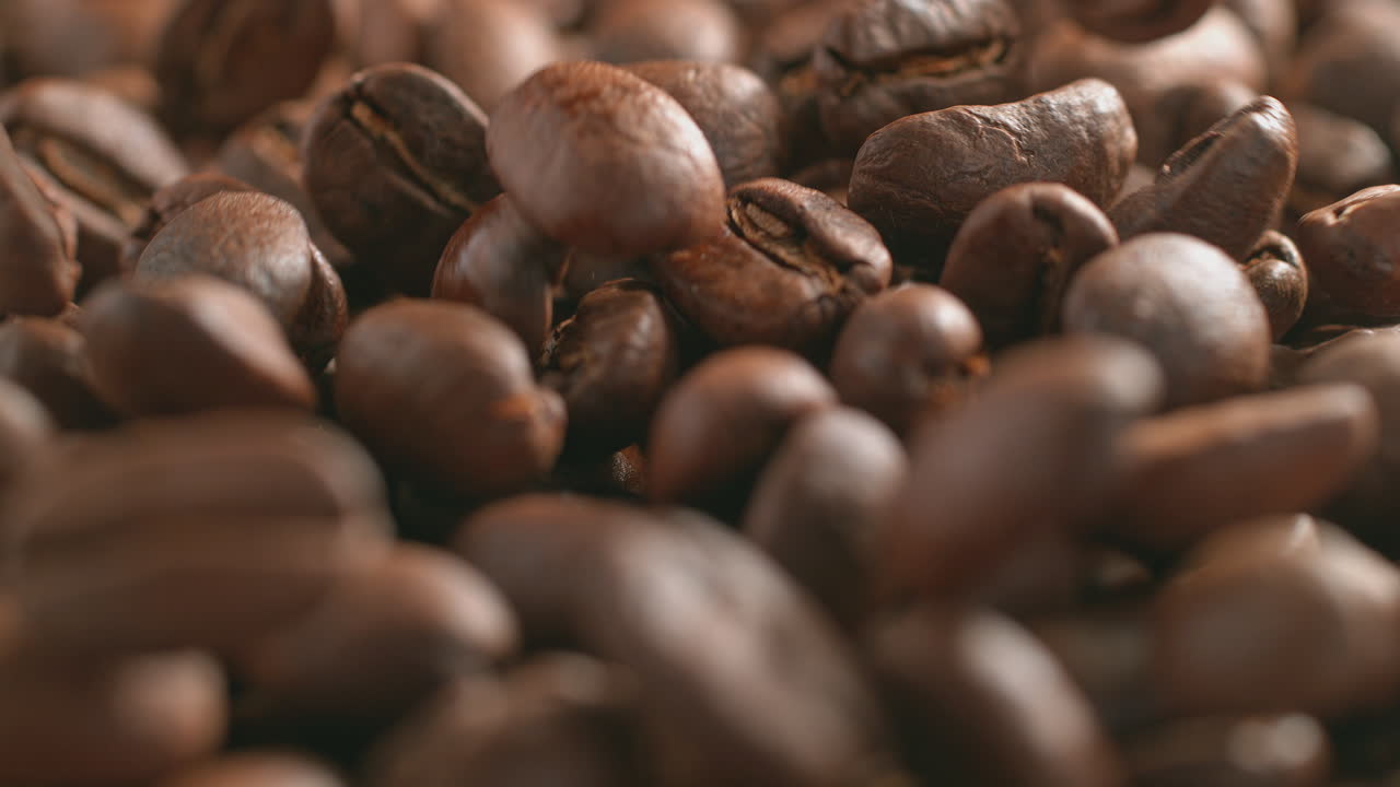 granos de café tostados cayendo y rodando en macro y cámara lenta