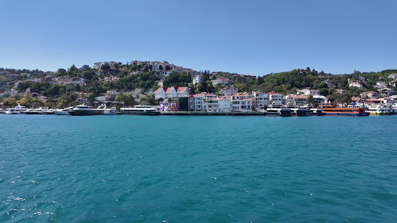 Bebek, İstanbul, Türkiye'deki Boğaz kıyı şeridi boyunca demirli tarihi yalı konaklarına, yamaç evlerine ve teknelere doğru sudan sahil manzarası.