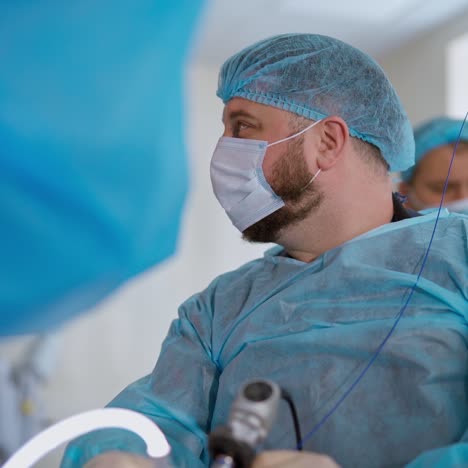surgeon with medical device. medical specialists conduct a laparoscopic surgery using modern equipment in clinic. side view of a doctor.