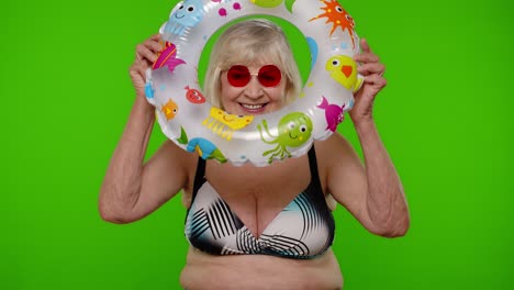 mujer anciana jubilada turista bailando, celebrando, sonriendo con un anillo de natación de goma en la llave de croma