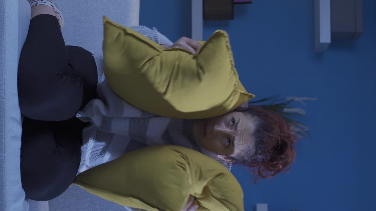 vídeo vertical de la mujer que presiona las almohadas en su cabeza con miedo.