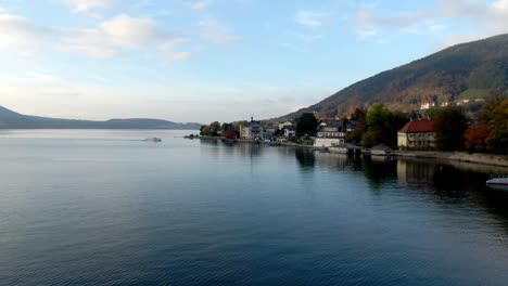 Aerial-lake-side-town-with-a-boat,-buildings-and-a-dock-in-Germany---Tegernsee,-Germany