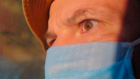joven con una máscara de protección mientras viaja en tren, autobús, coche. luz del sol en la cara del pasajero. emociones faciales del hombre viajero. concepto de vacaciones durante la pandemia de coronavirus covid-19