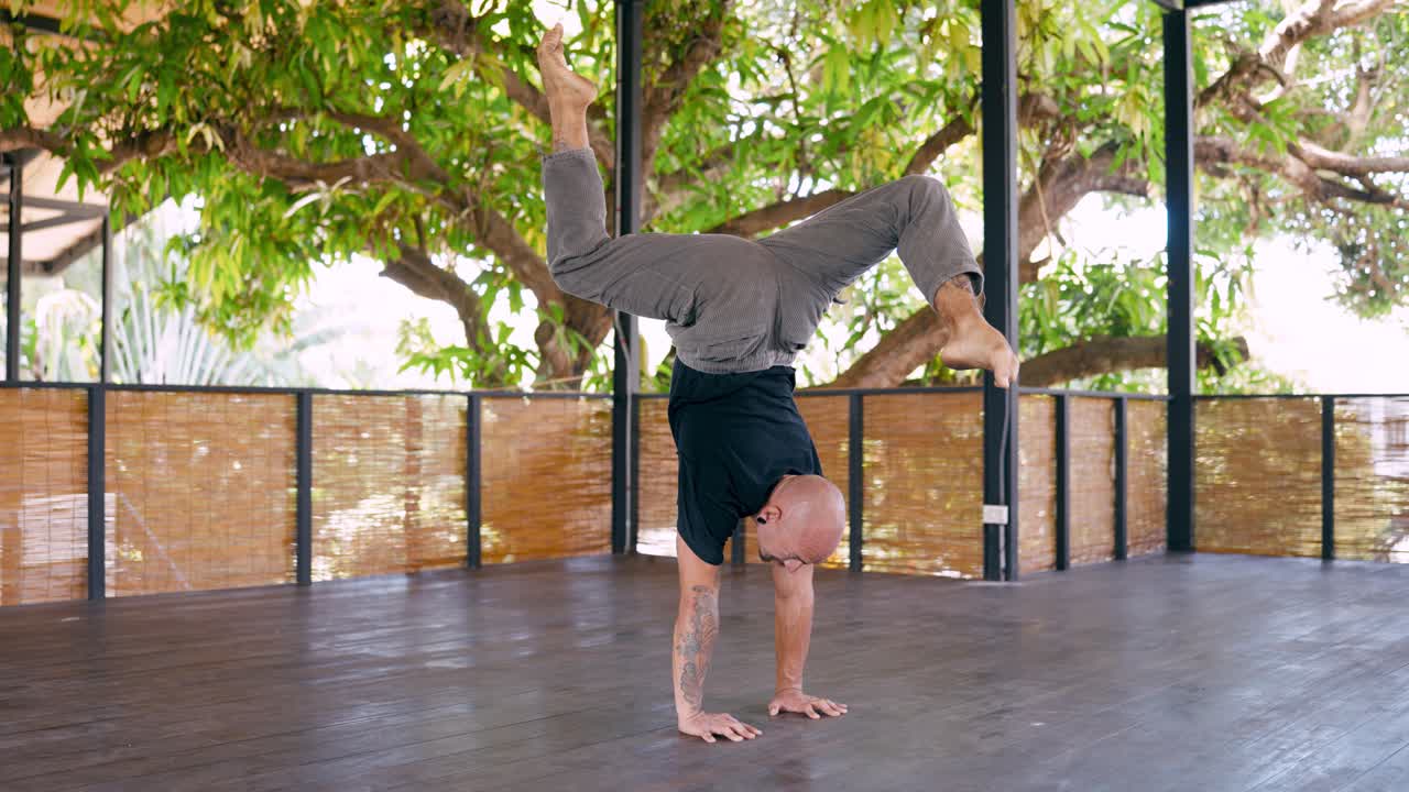 Man Performing Handstand with Spread Legs on Wooden Deck