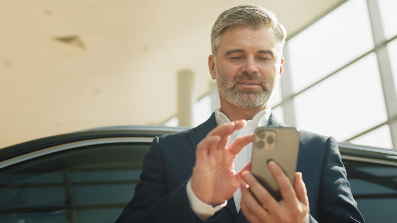 hombre de negocios usando un teléfono inteligente en una sala de exposición de automóviles