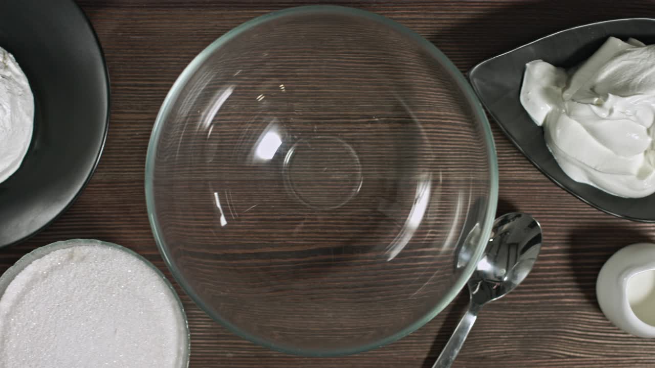 añadir ingredientes a un tazón de vidrio. manos masculinas haciendo postre. delicioso crema agria suave queso crema dulce. amasar los ingredientes. yogur casero natural fresco. relleno para eclairs. postre de cuajada.