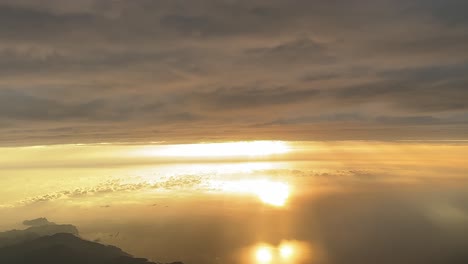 stunning sunset from the sky in a real flight, shot from a jet cockpit while flying under a layer of clouds over the mediterranean sea