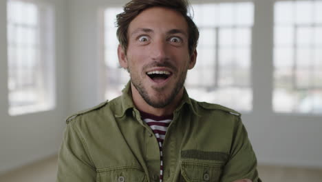 close-up-portrait-of-young-man-looking-surprised-at-camera-excited-arms-raised-winning-successful-caucasian-male-in-apartment-background