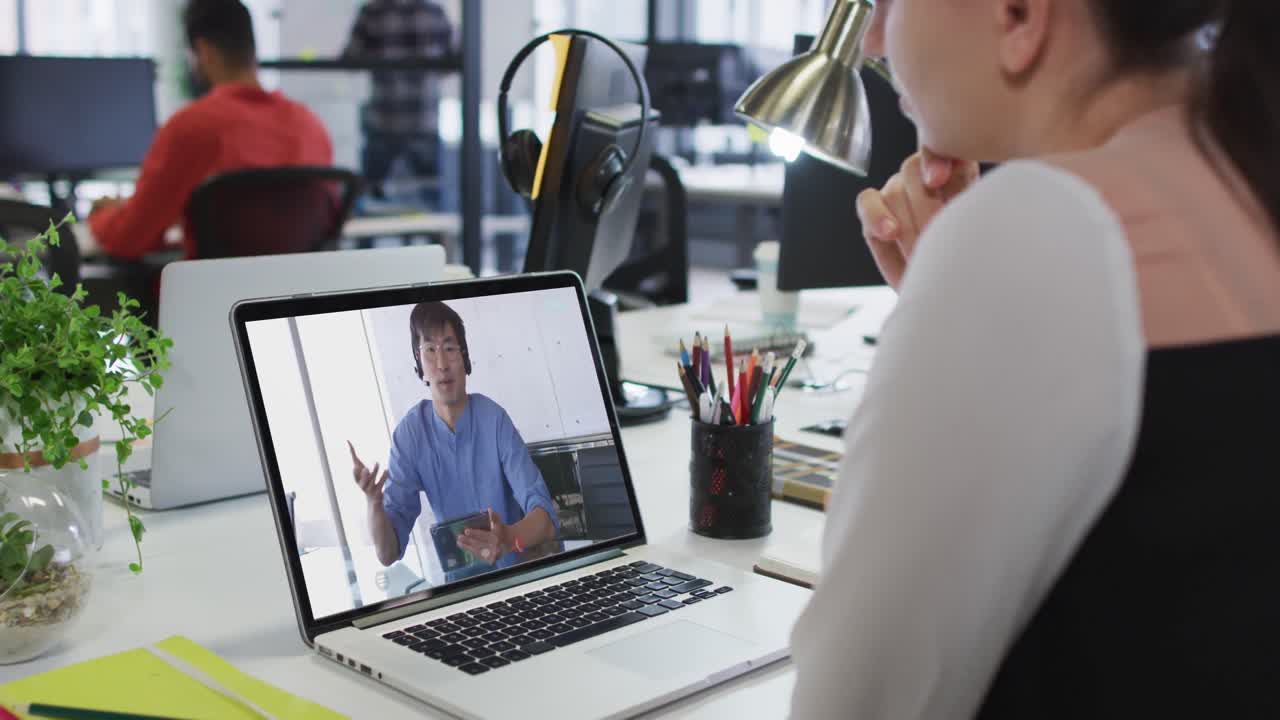 Caucasian woman having a video call with male colleague on laptop at office