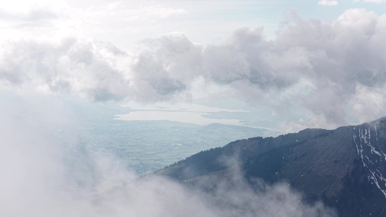 High-altitude aerial over Switzerland valley above clouds highlands