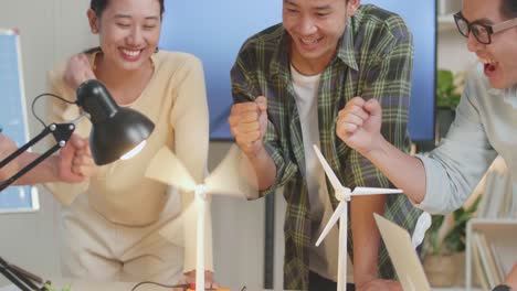 close up of happy asian engineers group celebrating succeed testing the wind turbine at the office
