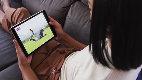 Composite-of-woman-sitting-at-home-on-couch-watching-baseball-game-on-tablet