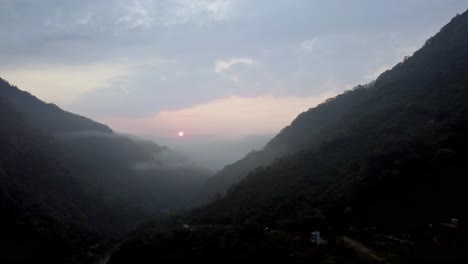 sunset over misty mountains with a glimpse of a winding road, serene evening
