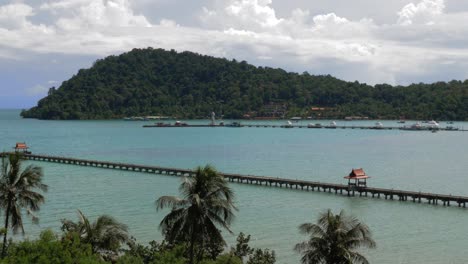 static shot of 2 piers in the ocean, one with red roofs and one with boats slowmo