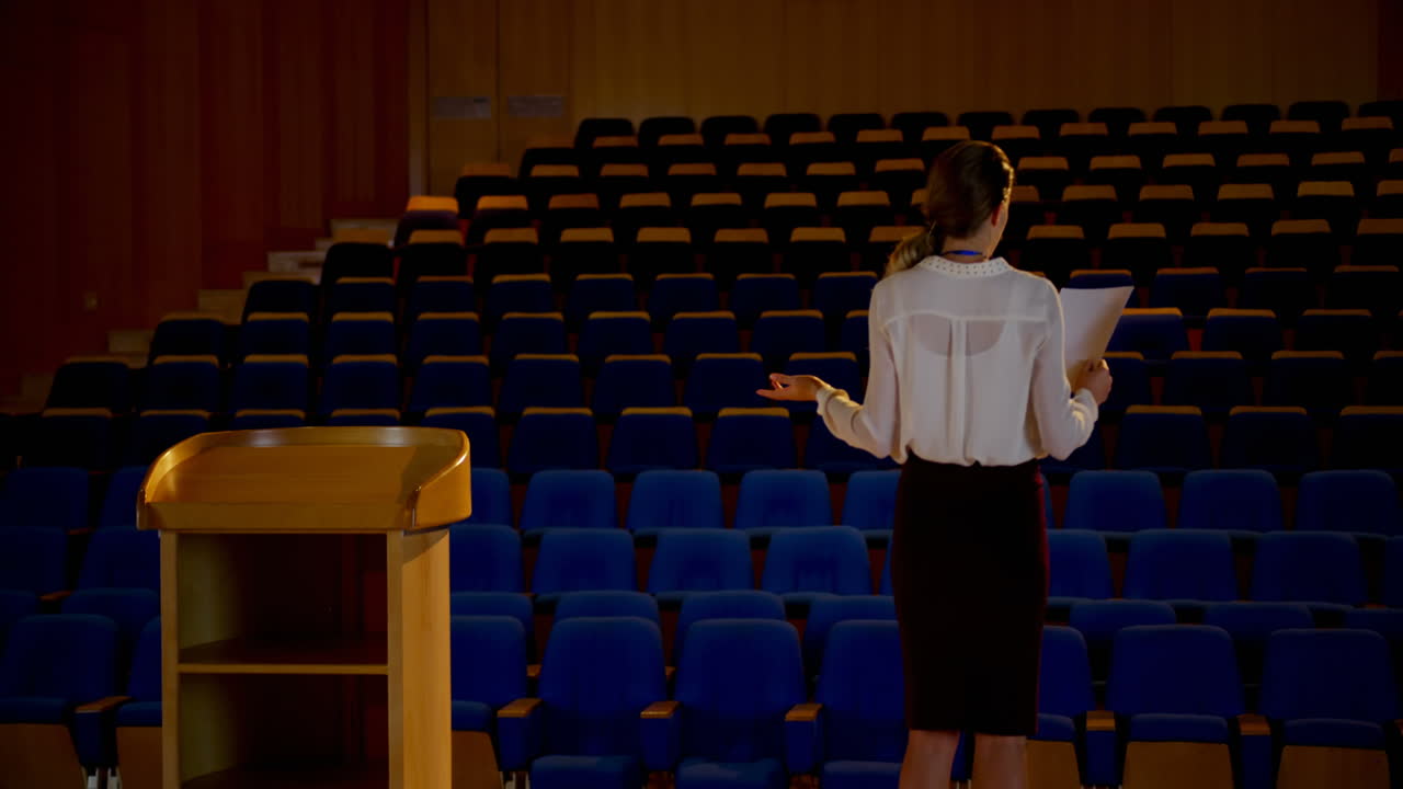 joven mujer de negocios caucásica practicando el discurso en un auditorio vacío 4k