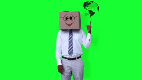 businessman wearing smiley face box pointing on globe against greenscreen