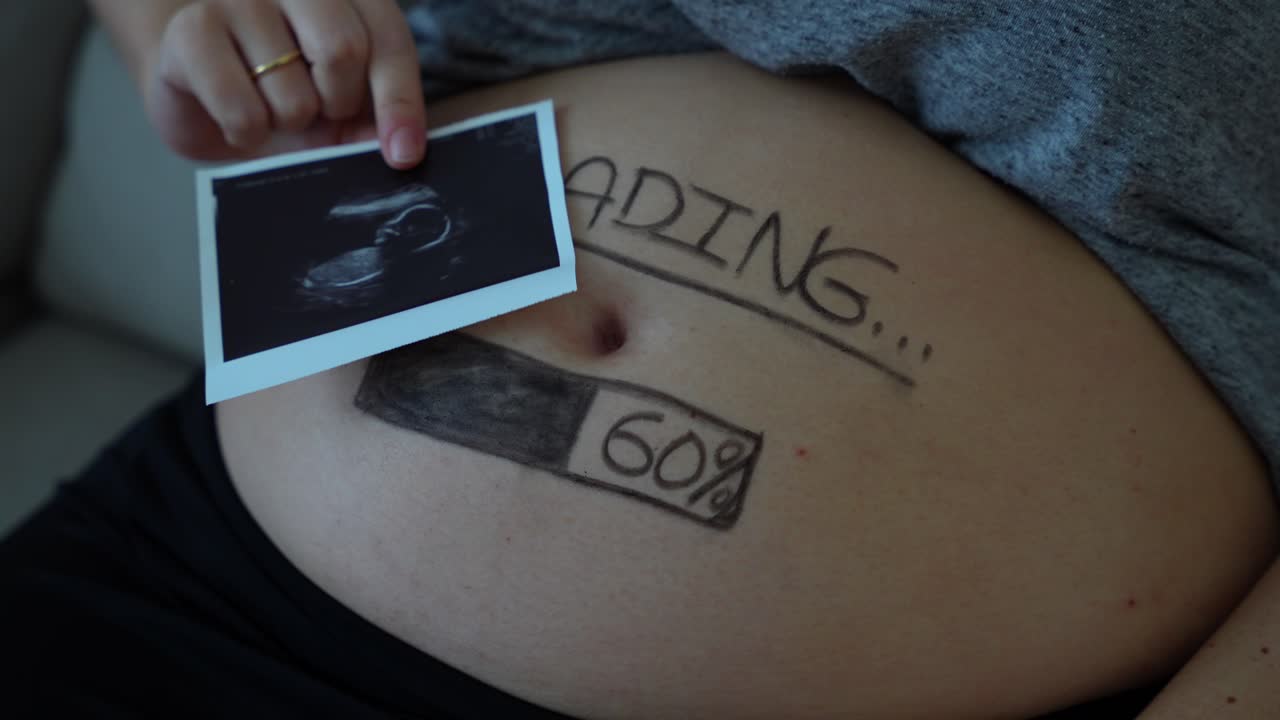 una barra de carga pintada en el vientre de una mujer embarazada y una imagen de ultrasonido de 24 semanas