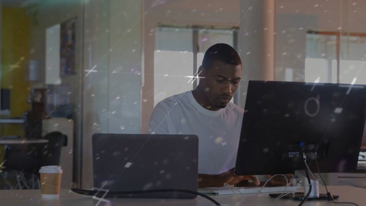 Man starting work, typing and shifting gaze between dual screens in tech while light streaks moving