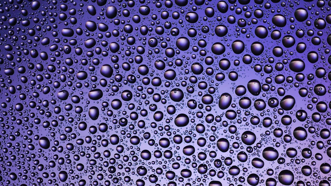 Texture di gocce d'acqua sul vetro giallo arancio - sfondo. Luce in movimento, colore cangiante.
