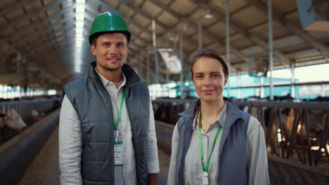 Portrait-livestock-team-posing-together-modern-cowshed-at-dairy-farm-facility