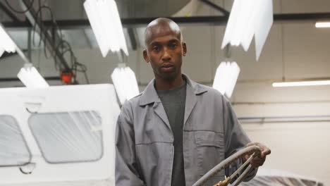 African-American-male-car-mechanic-holding-a-steering-wheel-and-looking-at-the-camera-