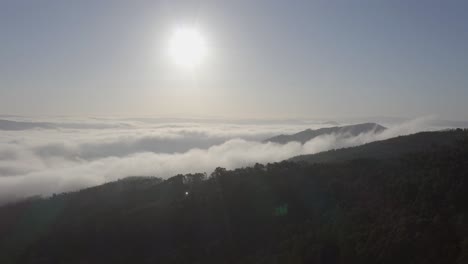 ascending drone shot over mountains in portugal covered with low clouds on a foggy day