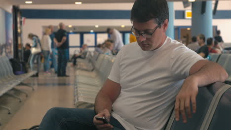 young man using cell phone in airport lounge