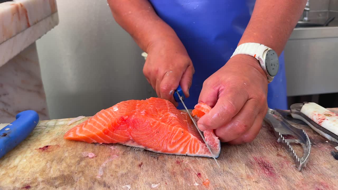 Close-up of hands filleting fresh salmon
