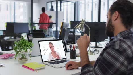 hombre de oriente medio teniendo una videollamada con una colega en una computadora portátil en la oficina